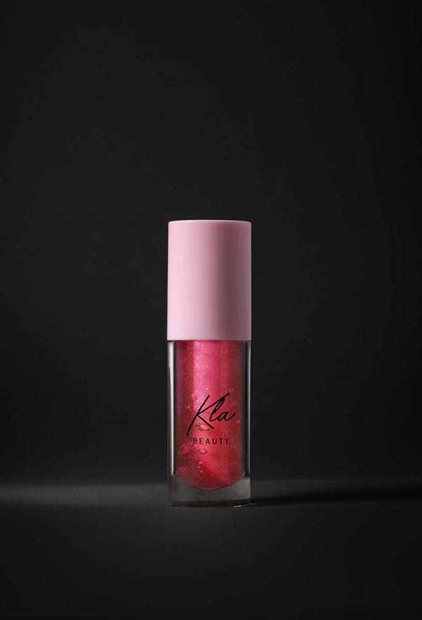 Glittery Pink Lip Oil by KLA Beauty in bottle, vegan and cruelty-free, hydrates lips with hyaluronic acid for glossy shine and softness.