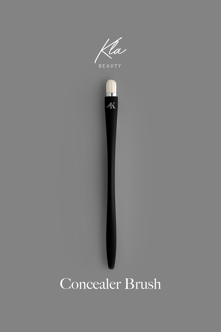 KLA-beauty concealer brush with sleek black handle and fine bristles on gray background