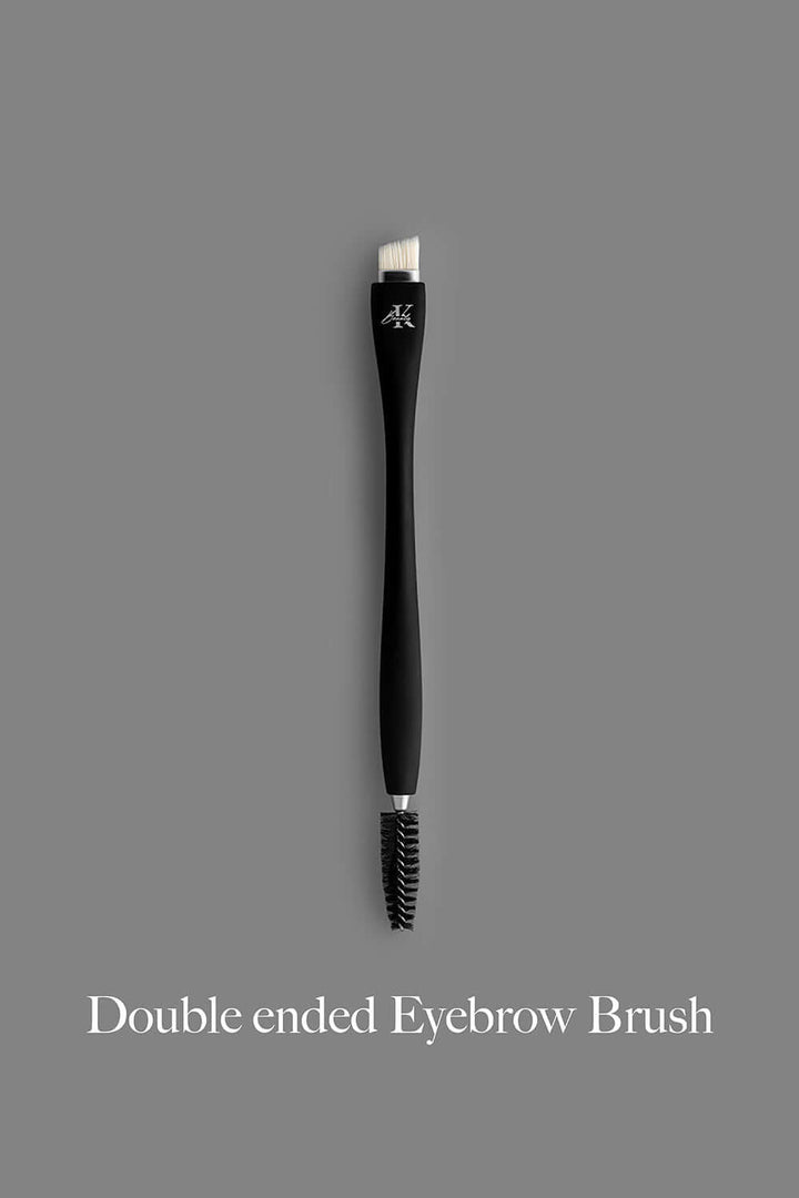 KLA-beauty double ended eyebrow brush with bristle and spoolie ends on a grey background